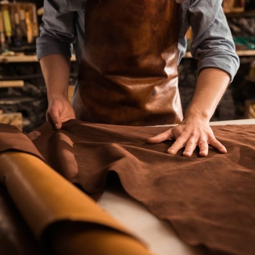 Close up of a cobbler working with leather textile Close up of a cobbler working with leather textile at his workshop